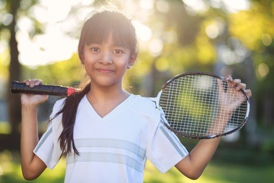 closeup cute little asian girl holding a badminton racket, outdoor