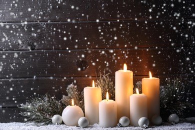 burning candles and fir branch on snow