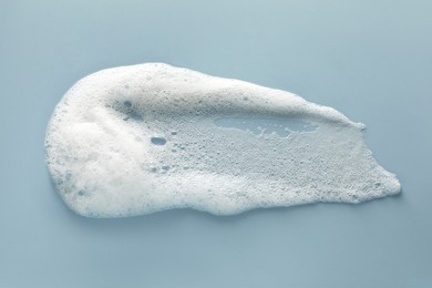 smudge of white washing foam on color background, top view