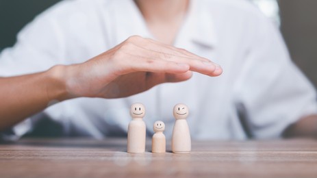 man's hand on a wooden doll refers to the protection and protection of safety ,concept of insurance management planning to ensure both health and financial safety,property and family risk reduction