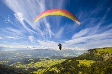 paraglider flying over mountains in summer day