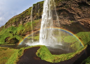 seljalandsfoss waterfall in iceland. summer sunny day. large rainbow decorates a drop of water. the picture was taken fisheye lens