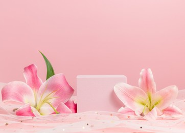 cube podium with pink lilies on pink background. display with flowers for product presentation. romantic, valentine concept