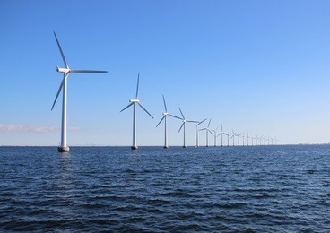 perspective line of ocean wind mills with dark water and sky