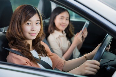 asian woman was driving with a friend to play the tablet