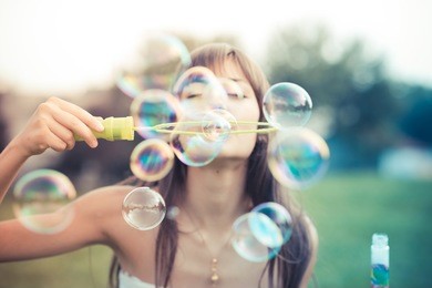 beautiful young woman with white dress blowing bubble in the city