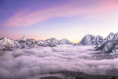 picturesque mountain valley filled with curly clouds at sunrise. the sacred ama dablam peak (6814 m) dominates on the left. nepal, himalayas. canon 5d mk ii. 
