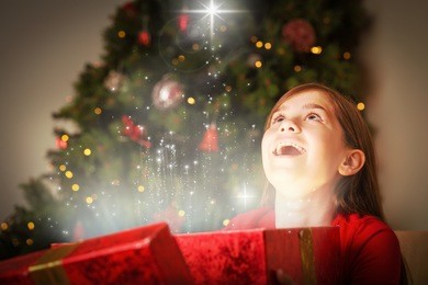 little girl opening a magical christmas gift against snow