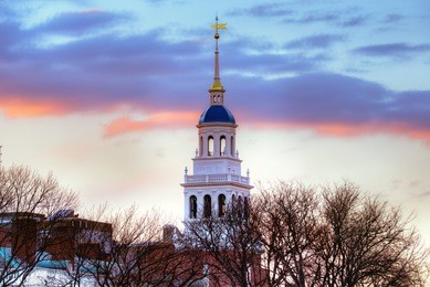 lowell house, harvard university. white bell tower, iconic blue dome, sunset sky, winter scene. 