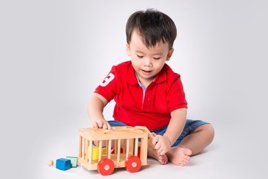 asian boy playing with the small colorful wooden car. little boy playing with cubes, smiling.