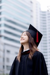 happy asian graduations girl standing front of college building.