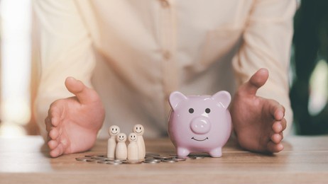 men show protection and safety protection to wooden dolls and piggy banks , the concept of insurance management planning, for both health and financial safety reduce risks to property and family