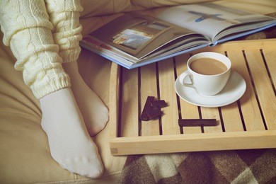 cozy winter: woman in warm socks with coffee and a book. retro toning