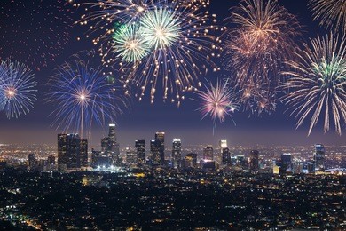 downtown los angeles cityscape with flashing fireworks celebrating new year's eve.