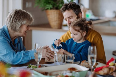 little girl unwraping gift at family dinner.