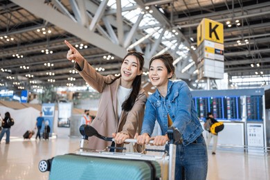 asian young women passenger walk in airport terminal to boarding gate. attractive beautiful female tourist friends feeling happy and excited to go travel abroad by airplane for holiday vacation trip.