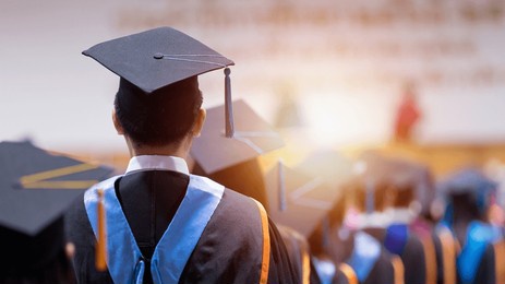 rear view of university graduates wearing graduation gown and cap in the commencement day