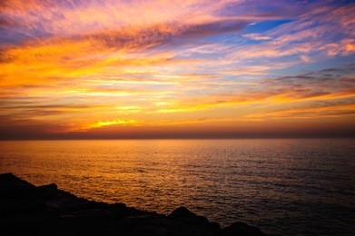 beautiful golden sunset in the sea with saturated sky and clouds. reflection in the water. rocky coastal line. peaceful serene landscape. nature background.