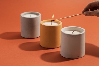 a hand lights a candle with a match stick. aromatic soy candles in gray concrete jar. poster banner for candle shop, beauty, spa