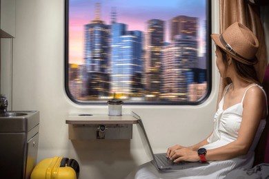 asian traveller woman take a cityscape photo by her smartphone on the train seat between working by computer notebook and on her travel trip