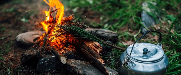 camping kettle near small camp fire close-up. cozy camping place in wild. wonderful evening atmospheric background of campfire. beautiful flame of small magic bonfire. romantic warm place with fire.