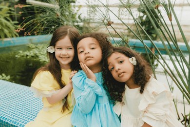 three little girls in the garden. children of different nationalities. two swarthy babies and one white girl.
