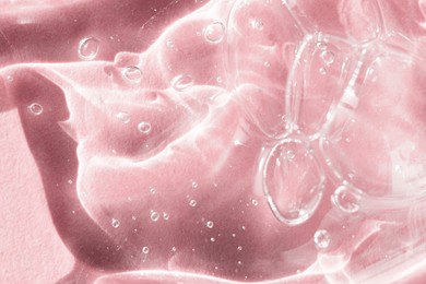 liquid cosmetic texture on a pink background top view. bubbles of care products, moisturizing gel close-up.