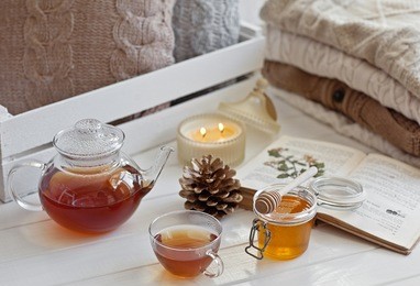 cozy wool winter accessory. warm sweaters candle, tea and cone