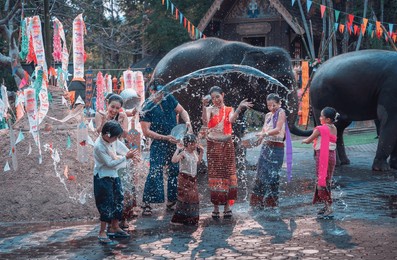 asian people wearing thai dress traditional playing splash water with pile of sand pagodas, kite paper and thai elephant at temple during songkran festival is funny festival traditional holiday