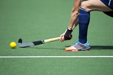 field hockey player, forcefully passing the ball to a tream mate