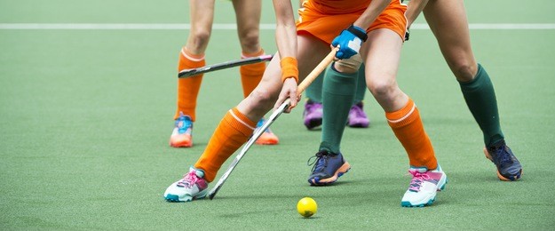 field hockey players challenge eachother for possession of the ball on the midfield battle of a hockey mach