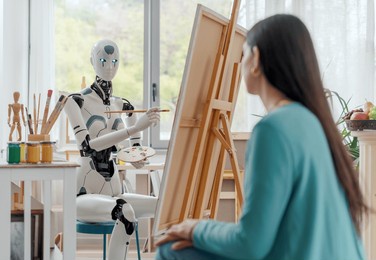creative ai robot painting a portrait on canvas in the art studio, a model is posing in the foreground