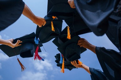 close-up of graduation ceremony university high school graduates throwing cap on the blue sky.