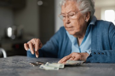 senior woman counting her money at home.