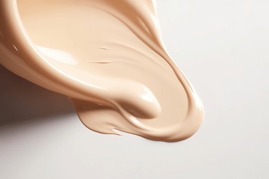 liquid foundation strokes on light color background, makeup creamy texture, skin tone cosmetic product smear smudge swatch