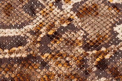 snakeskin pattern on genuine leather close-up, imitation of exotic reptile, surface of bright brown color, trendy background