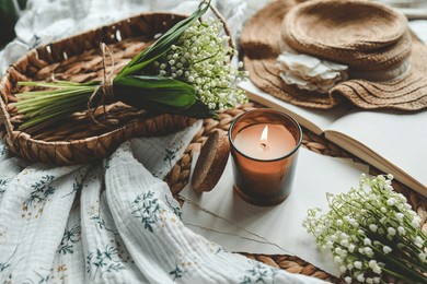 burning candle and bouquet of lilies of the valley, aesthetic home atmosphere.