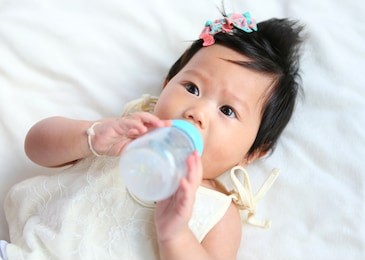 asian baby infant eating milk from bottle