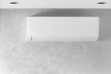 white air conditioner on a gray wall in a house, apartment, copy space. air conditioning system. the indoor unit of a split system for cooling and heating the room. wall type air conditioner.