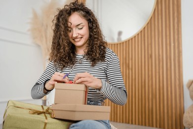 one young woman wrap presents at home happy female smile while holding wrapping paper ans gift box prepare to pack gifts for holiday season happy smile copy space real people