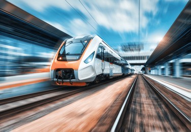 high speed train in motion on the railway station at sunset. modern intercity passenger train with motion blur effect on the railway platform. industrial. railroad in europe. commercial transportation
