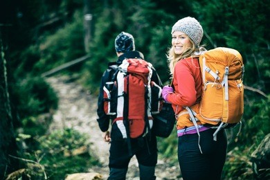 man and woman hikers trekking in mountains. young couple walking with backpacks in forest, tatras in poland. old vintage photo style.