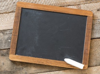 blackboard with piece of chalk on wooden background