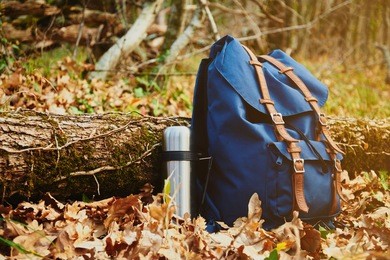 thermos and backpack outdoors on autumn nature, hiking theme