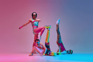 athletic, funny men in retro colorful sportswear training, doing exercises against gradient blue pink studio background in neon light. concept of sportive and active lifestyle, humor, retro style. ad
