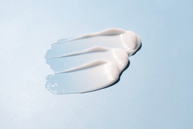 texture of white cream on blue background. smear of moisturizer close up. lotion swatch. beauty skin care product smear smudge. spf sunscreen cream sample on blue background