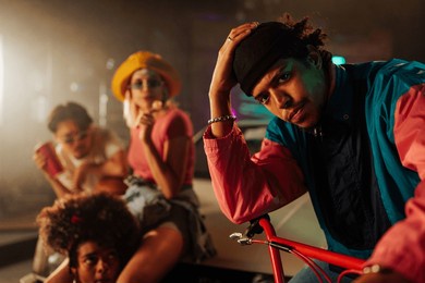 an african american stylish man is outdoors with his retro friends hanging out in the evening.