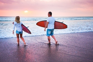 couple of surfers walking on coast in indonesia, bali, kuta