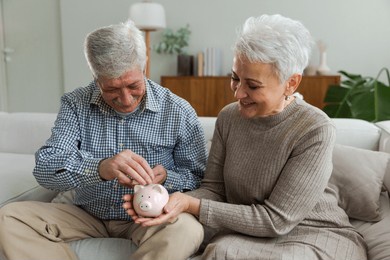 saving money investment for future. senior adult mature couple holding piggy bank putting money coin. old man woman counting saving money planning retirement budget. saving investment banking concept