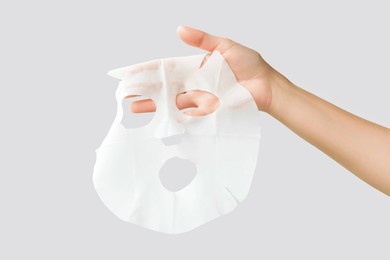 hand holding moisturising face mask isolated on gray background